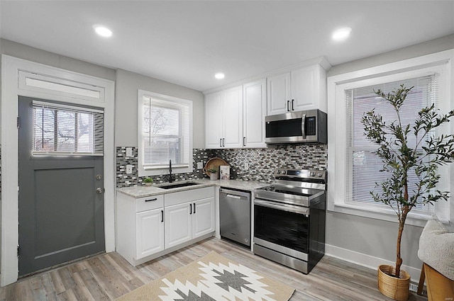 kitchen featuring white cabinets, appliances with stainless steel finishes, light hardwood / wood-style floors, and sink