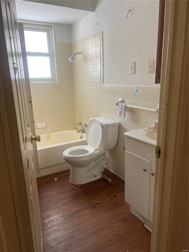 full bathroom featuring toilet, tiled shower / bath combo, hardwood / wood-style floors, tile walls, and vanity