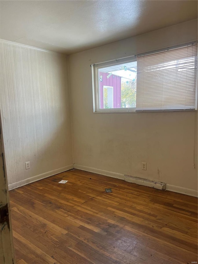 empty room featuring dark wood-type flooring and baseboard heating