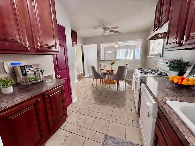 kitchen with a sink, white appliances, reddish brown cabinets, and under cabinet range hood