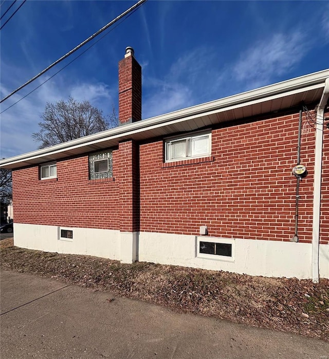 view of home's exterior with brick siding and a chimney