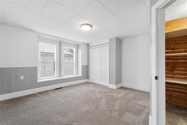 carpeted empty room featuring a drop ceiling