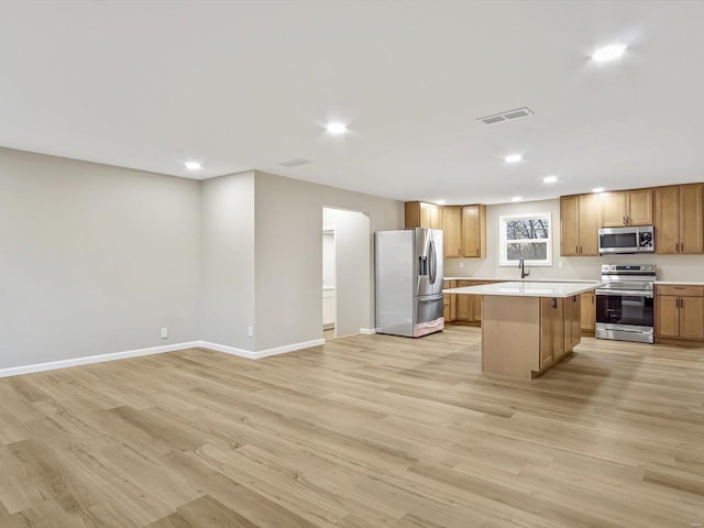 kitchen with sink, a center island, light hardwood / wood-style flooring, and appliances with stainless steel finishes