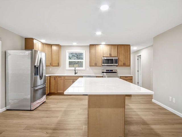 kitchen with light hardwood / wood-style flooring, appliances with stainless steel finishes, sink, a center island, and a breakfast bar