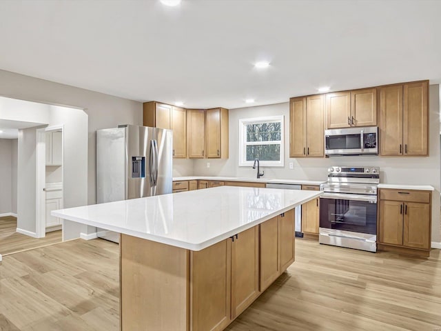 kitchen featuring sink, light wood-type flooring, a center island, and appliances with stainless steel finishes