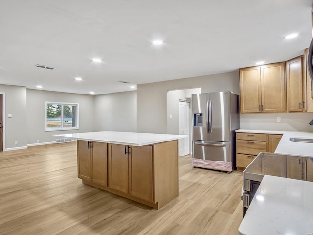 kitchen featuring sink, stainless steel fridge, light hardwood / wood-style flooring, and a kitchen island