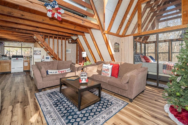 living room featuring wood walls, lofted ceiling with beams, and light hardwood / wood-style floors