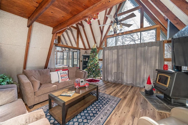 sunroom / solarium featuring a wood stove, ceiling fan, plenty of natural light, and vaulted ceiling with beams