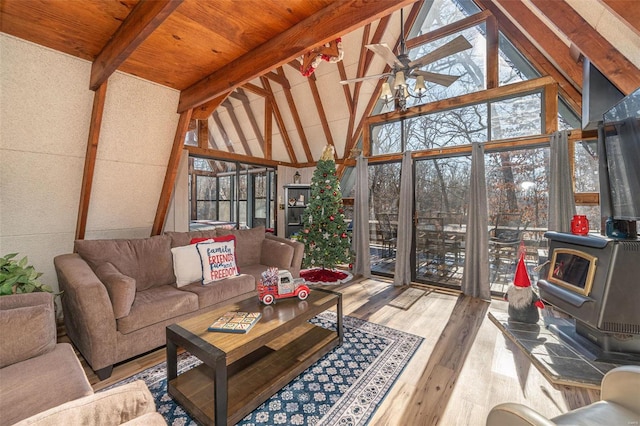 sunroom / solarium with lofted ceiling with beams, a wood stove, plenty of natural light, and ceiling fan