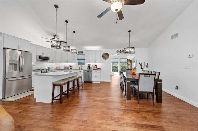 dining area featuring light hardwood / wood-style floors, high vaulted ceiling, and ceiling fan