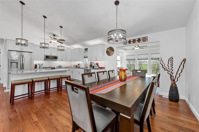 dining room featuring ceiling fan with notable chandelier and dark wood-type flooring