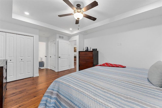 bedroom with a raised ceiling, ceiling fan, dark hardwood / wood-style flooring, and a closet