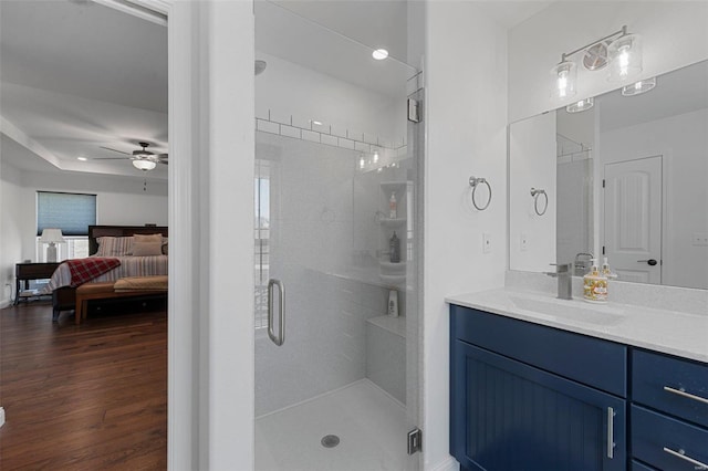 bathroom with hardwood / wood-style flooring, ceiling fan, walk in shower, and vanity