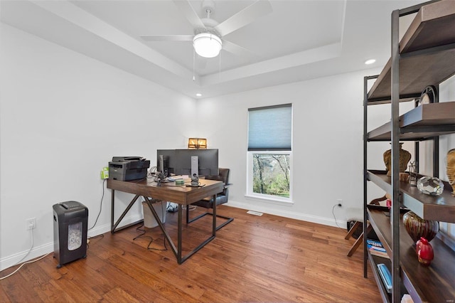 office space with wood-type flooring, a tray ceiling, and ceiling fan