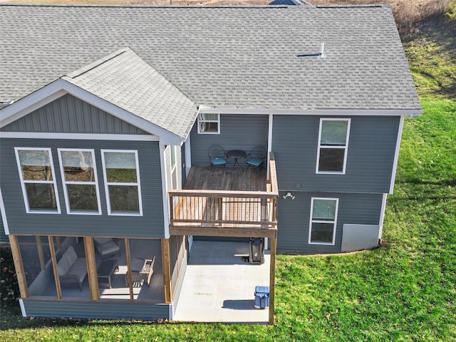 rear view of house featuring a lawn, a sunroom, and a wooden deck