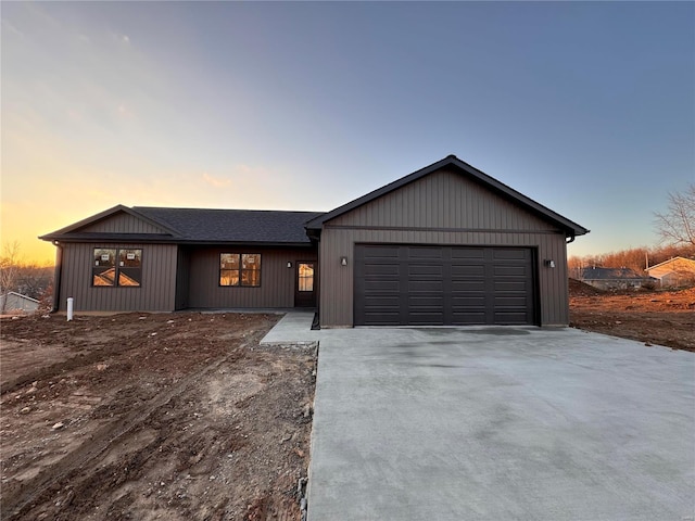 view of front of house featuring a garage, driveway, and roof with shingles