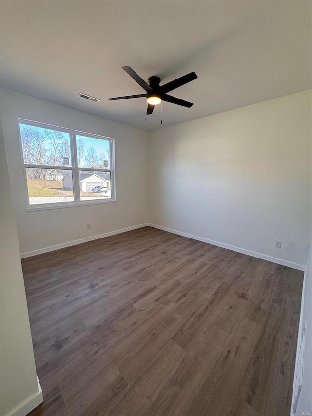 unfurnished room with a ceiling fan, baseboards, visible vents, and dark wood-style flooring