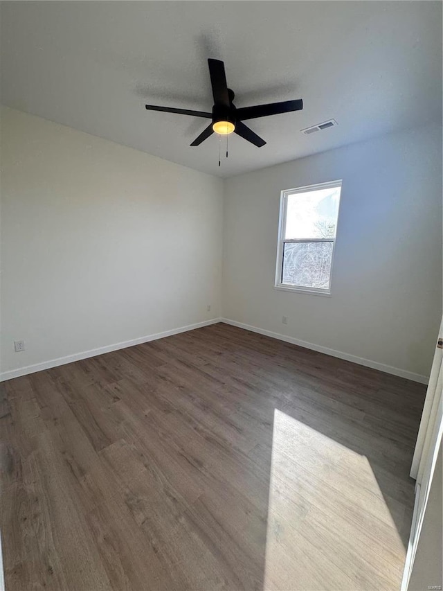 unfurnished room with a ceiling fan, wood finished floors, visible vents, and baseboards