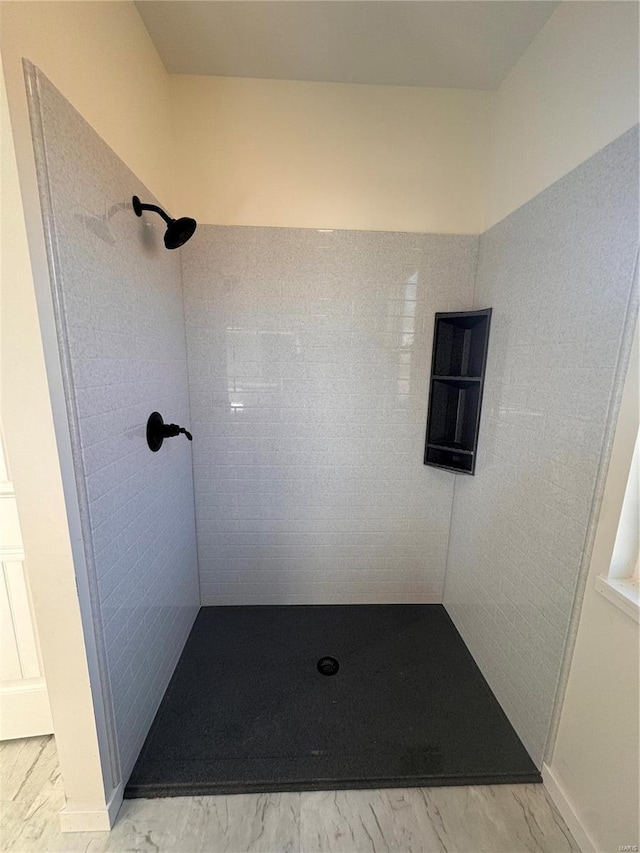 bathroom featuring a tile shower and marble finish floor