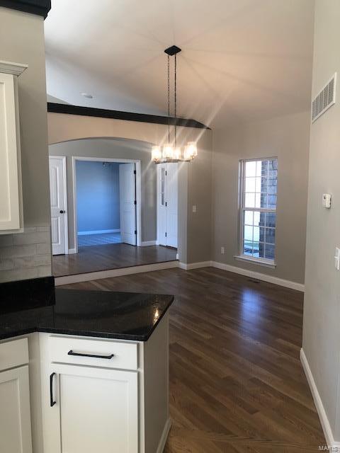 kitchen with decorative backsplash, dark wood-type flooring, white cabinets, a chandelier, and hanging light fixtures