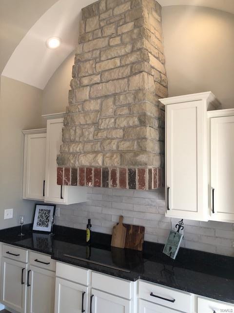 kitchen featuring white cabinets, lofted ceiling, and tasteful backsplash