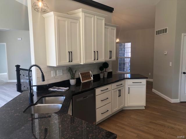 kitchen featuring white cabinetry, dishwasher, sink, dark stone counters, and decorative backsplash