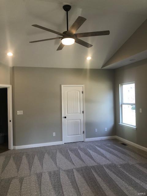 carpeted spare room featuring vaulted ceiling and ceiling fan