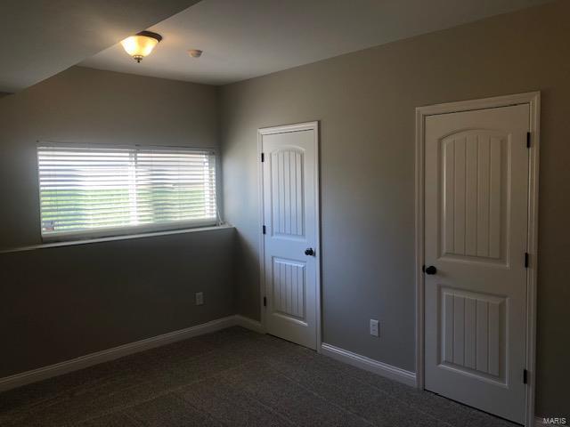 unfurnished bedroom with dark carpet and a closet