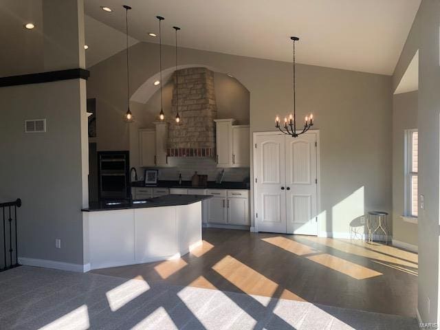 kitchen featuring pendant lighting, white cabinetry, high vaulted ceiling, and tasteful backsplash