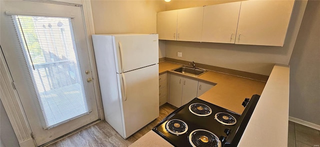 kitchen featuring white fridge, white cabinets, stove, and sink