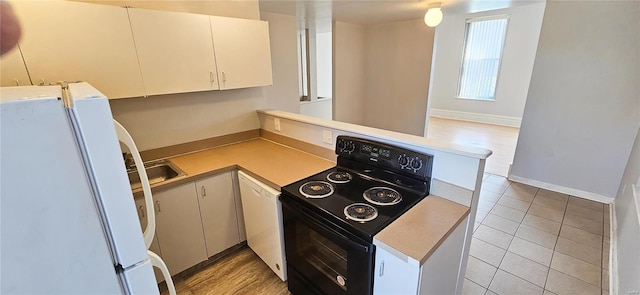 kitchen featuring white fridge, kitchen peninsula, light tile patterned floors, white cabinets, and black / electric stove