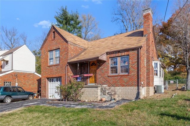 view of front of home with a front yard, a garage, and cooling unit