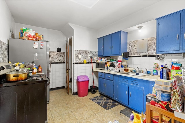 kitchen featuring blue cabinets, sink, light tile patterned floors, tile walls, and stainless steel appliances