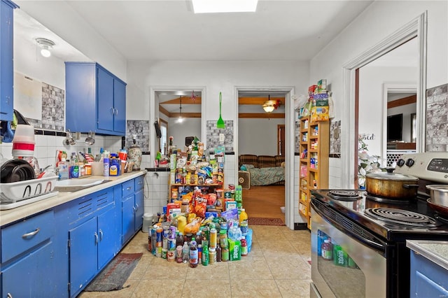 kitchen featuring sink, blue cabinetry, light tile patterned floors, tile walls, and stainless steel range with electric cooktop