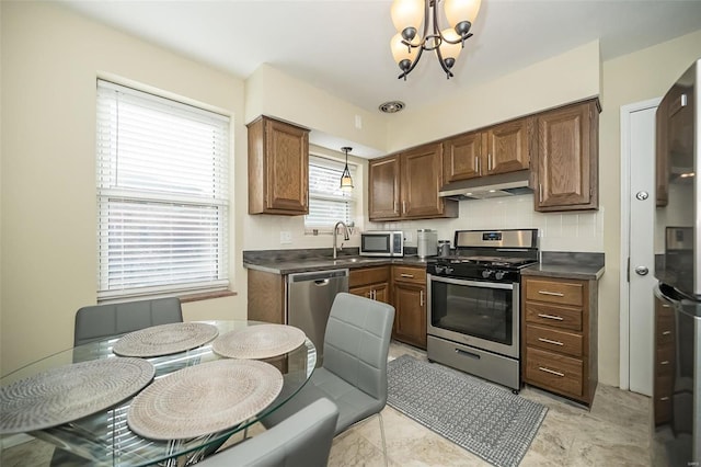 kitchen featuring sink, stainless steel appliances, tasteful backsplash, a chandelier, and pendant lighting