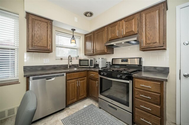 kitchen with backsplash, sink, decorative light fixtures, and appliances with stainless steel finishes