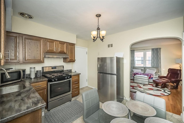 kitchen featuring sink, stainless steel appliances, a chandelier, decorative light fixtures, and light wood-type flooring