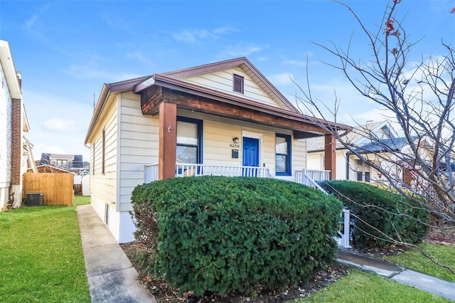 bungalow-style home with a porch, a front yard, and cooling unit