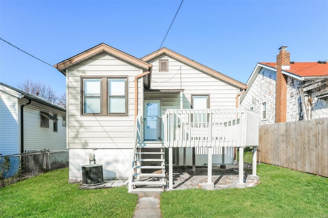 back of property with a lawn, a wooden deck, and central AC unit