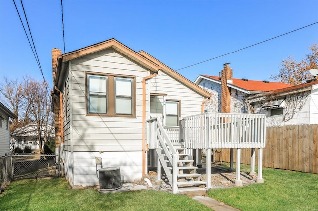 rear view of property with a wooden deck, a yard, and cooling unit