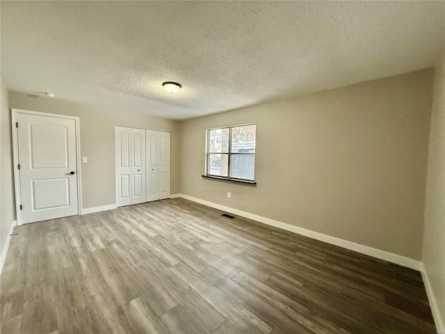 unfurnished bedroom featuring hardwood / wood-style flooring, a textured ceiling, and a closet