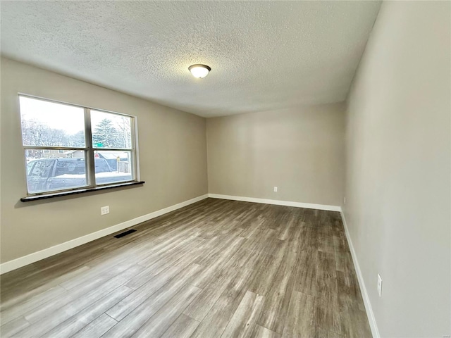 spare room with hardwood / wood-style floors and a textured ceiling