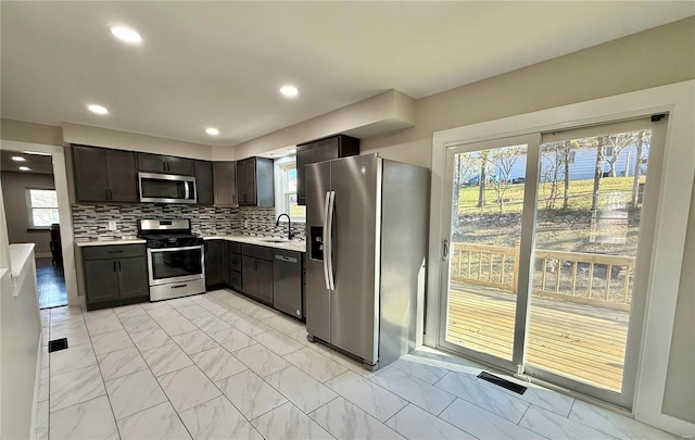 kitchen featuring dark brown cabinets, sink, decorative backsplash, and stainless steel appliances