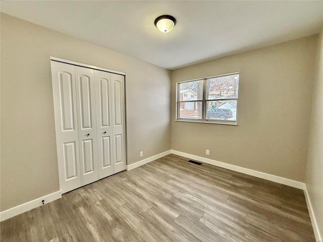 unfurnished bedroom with light wood-type flooring and a closet