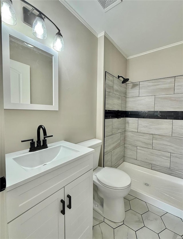 bathroom featuring crown molding, toilet, tiled shower, and vanity