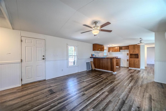 kitchen with vaulted ceiling, ceiling fan, kitchen peninsula, and dark hardwood / wood-style flooring