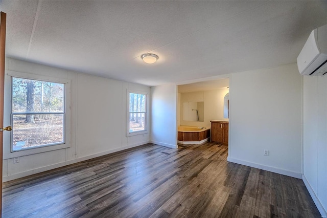 spare room featuring a wall mounted air conditioner, a wealth of natural light, and dark hardwood / wood-style floors