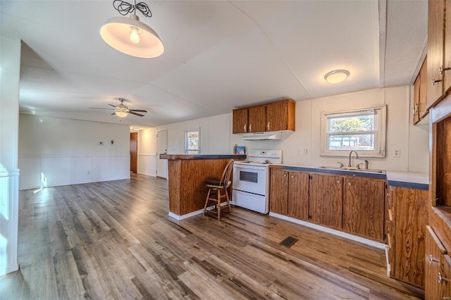 kitchen featuring wood-type flooring, sink, kitchen peninsula, ceiling fan, and electric range