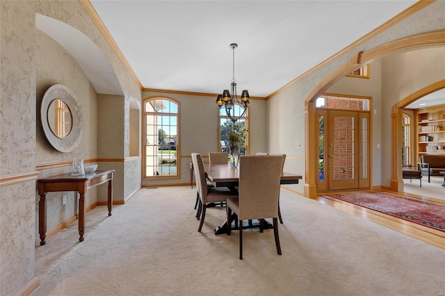 dining area with crown molding, an inviting chandelier, and light carpet