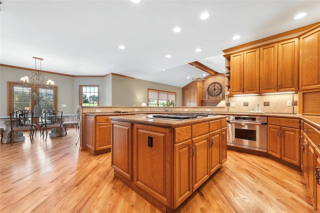 kitchen with kitchen peninsula, a chandelier, decorative light fixtures, stainless steel appliances, and a kitchen island